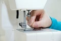 Caucasian girl inserts a thread into the needle of the sewing machine. Royalty Free Stock Photo