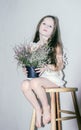 Caucasian girl leaned on a wooden chair in a white dress on a white background