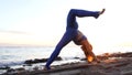 Caucasian girl practicing camatkarasana yoga asana on seashore at sunset.