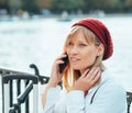 Caucasian girl in a red beret, talking on the phone by the lake fence of the Parque del Retiro in Madrid, Spain Royalty Free Stock Photo