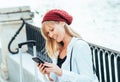 Caucasian girl in a red beret, talking on the phone by the lake fence of the Parque del Retiro in Madrid, Spain Royalty Free Stock Photo