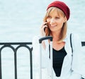 Caucasian girl in a red beret, talking on the phone by the lake fence of the Parque del Retiro in Madrid, Spain Royalty Free Stock Photo