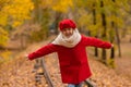 Caucasian girl in a red coat and beret walks along the railway tracks in the park in autumn. Royalty Free Stock Photo