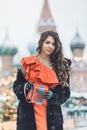 Caucasian girl in a red dress plays on an accordion in the winter a blizzard against the background of St. Basil` Royalty Free Stock Photo