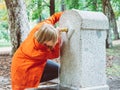 Caucasian girl with red gabardine drinks water from a fountain in a park in Madrid