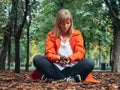 Caucasian girl with red gabardine plays on the ground with autumn leaves