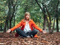 Caucasian girl with red gabardine plays on the ground with autumn leaves