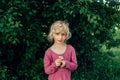 Caucasian girl in red pink dress guessing fortune on white daisy flower. Royalty Free Stock Photo