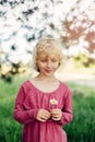 Caucasian girl in red pink dress guessing fortune on white daisy flower. Royalty Free Stock Photo