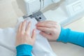 Caucasian girl sews cotton white fabric on the sewing machine Royalty Free Stock Photo