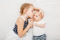 Caucasian girl sister holding kissing little baby, lying on bed