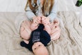 A caucasian girl sitting on the bed and playing with her baby sibling holding its feet Royalty Free Stock Photo