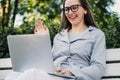 Caucasian girl sitting on a park bench and video chatting via laptop Royalty Free Stock Photo
