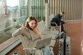 Caucasian girl sitting in waiting room with laptop near valise. Royalty Free Stock Photo