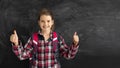 caucasian girl student in the classroom near the chalk board. Raises two fingers up. Online education and e-learning Royalty Free Stock Photo