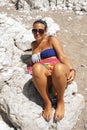 A gorgeous young woman lying down on a boulder at the beach. Royalty Free Stock Photo