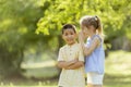 Caucasian girl telling secret to asian boy in the park