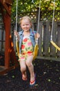 Caucasian girl toddler on swing on backyard playground outside Royalty Free Stock Photo
