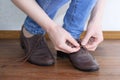 Caucasian girl tying shoelaces on brown shoes. Royalty Free Stock Photo