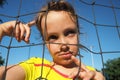 A Caucasian girl 8 years old stands behind a sports net and looks up thoughtfully. Grimace on the face. Volleyball Royalty Free Stock Photo