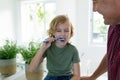 Caucasian grandfather in bathroom with grandson brushing teeth sitting beside basin