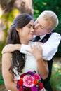 Caucasian groom lovingly kissing his biracial bride on cheek. Di