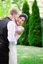 Caucasian groom lovingly kissing his biracial bride on cheek. Di