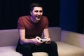 Caucasian guy playing video game and using joystick . Handsome young man enjoying free time alone while sitting on couch Royalty Free Stock Photo