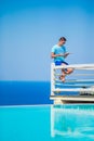 Caucasian guy relaxing near pool with amazing view and reading book in Greece. Beautiful famous background Royalty Free Stock Photo