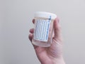 Caucasian hand holding a urine sample cup inside a hospital restroom Royalty Free Stock Photo