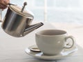 Hand pouring tea from silver metal teapot Royalty Free Stock Photo