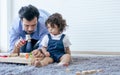 Caucasian handsome beard father or daddy wearing shirt with necktie, lying down on the floor, taking care and playing toys with Royalty Free Stock Photo