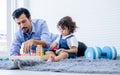Caucasian handsome father taking care, playing toys with his little cute daughter on floor in cozy living room at home after work Royalty Free Stock Photo