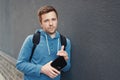 Caucasian handsome man in casual clothes with a friendly smile leaning against wall with a rough texture outdoors Royalty Free Stock Photo