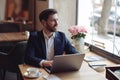 Caucasian handsome man looking at window, sitting at laptop on table in cafe. Business. Royalty Free Stock Photo