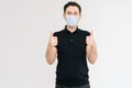 Caucasian handsome man with medical mask in black t-shirt showing thumbs up gesture