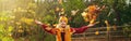 Caucasian happy smiling woman girl in warm yellow scarf and hat throwing autumn fall orange red leaves in park forest outdoor. Royalty Free Stock Photo