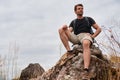 Caucasian hiker hiking on trail to mountain peak and resting on rock for his success