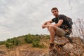 Caucasian hiker hiking on trail to mountain peak and resting on rock for his success