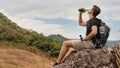 Caucasian hiker hiking on trail to mountain peak and resting on rock for his success