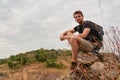 Caucasian hiker hiking on trail to mountain peak and resting on rock for his success