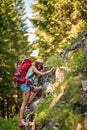 Caucasian hiker woman climbing cliff in forest. Backpacker girl in casual clothes. Hiking, lifestyle, nature concept
