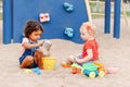 Caucasian and hispanic latin babies children sitting in sandbox playing with plastic colorful toys Royalty Free Stock Photo