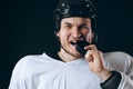 Hockey player bites the puck with broken teeth and looking at camera with a grin.