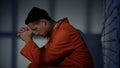 Caucasian imprisoned male praying in cell, feeling guilty and asking for mercy