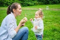 A Caucasian kid with his mother runs in the park in the summer for soap bubbles Royalty Free Stock Photo