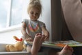 Caucasian kid reads a book, sitting near window, little cute child leaning. Royalty Free Stock Photo