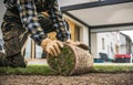 Caucasian Landscaper Installing Roll of New Natural Grass Turf