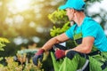 Professional Gardener Sitting in the Garden with Pruning Shears in Hand