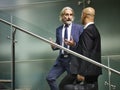 Caucasian and latino business men having a conversation while walking on stairs in modern office building Royalty Free Stock Photo